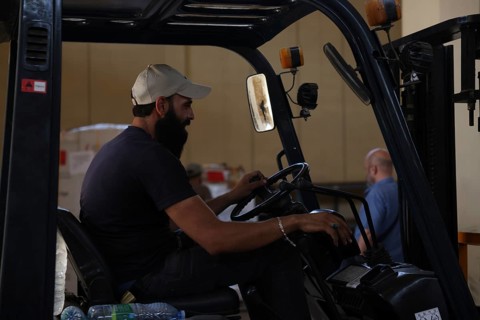 Relief workers unload boxes of medical aid provided by Qatar at Damascus International Airport,