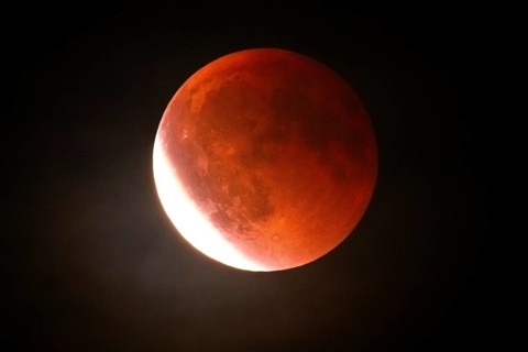 After a total lunar eclipse, the moon appears shortly after its rise in the evening sky as a