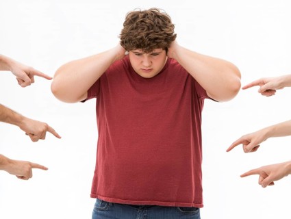 Overweight boy being judged by pointing fingers, symbolising fatshaming, bullying, judgement and