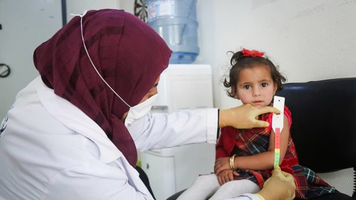 A doctor examines children's malnutrition inside a refugee camp. Malnutrition was measured using a
