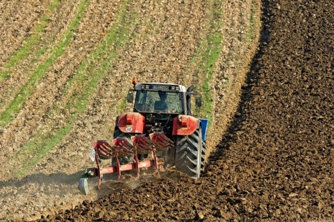 Harvested grain field being turned into a field by Steyr tractor with plough, Hohenpolding, Erding,