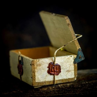 A wooden box is secured with twine, featuring a deep red wax seal that signifies authenticity and