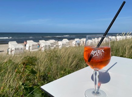 Glass of Aperol Spritz on a table overlooking the beach, Baltic resort Kühlungsborn,