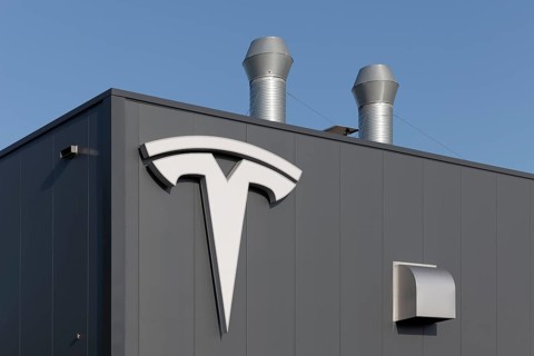 Tesla, logo on modern workshop building, figurative mark without lettering, US car manufacturer for