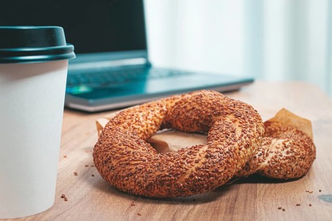 Simits with coffee on a wooden table, with a laptop, in a cozy working environment, snack,