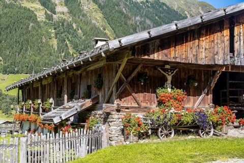Colourful floral decorations and crucifix at a rustic alpine hut, Ridnauntal, South Tyrol, Italy