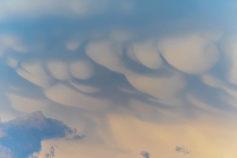 Unusual cloud structures create captivating shapes against a backdrop of warm colours as the sun