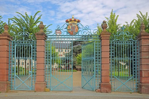 Gate entrance with metal gate, decorations and coat of arms, white tower, wrought ironwork,