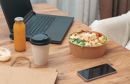 Work at home on a laptop, there is food on the table, salad, coffee and juice, delivery, there are