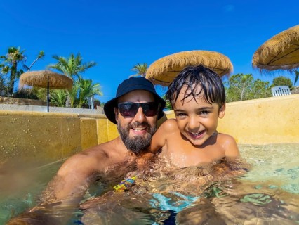Happy father and son are spending quality time together, playing in swimming pool during summer