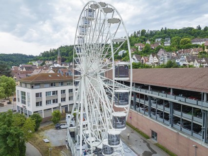A large Ferris wheel in the middle of an urban environment with a cloudy sky, Ferris wheel