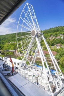 Incompletely constructed Ferris wheel, embedded in a green landscape with villages, Ferris wheel