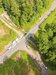 A railway crossing in the middle of a forest with several roads and vehicles, construction of the