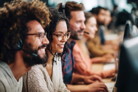 Diverse employees in corporate environment support center analyzing data and helping customers to
