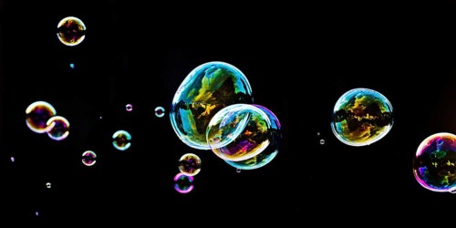 Iridescent soap bubbles in the colours of the rainbow against a black background, Recklinghausen,