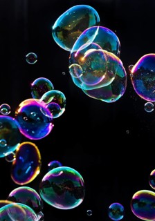 Iridescent soap bubbles in the colours of the rainbow against a black background, Recklinghausen,