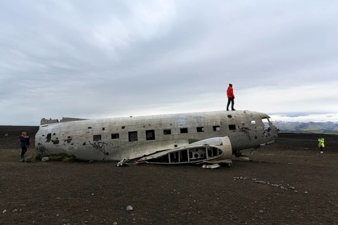Tourist on aircraft wreckage, US Navy Douglas DC-3 transport plane, Sander, volcanic landscape,