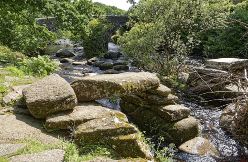 Remains of an old stone bridge and the new bridge on the East Dart River in Dartmoor National Park.