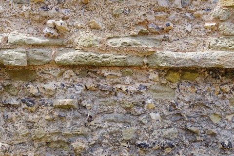 Masonry of the historic castle wall of Pevensey Castle, a Norman castle, in the village of