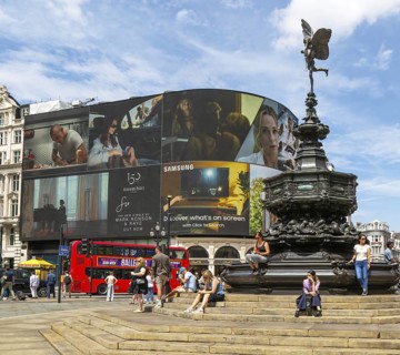 People sitting around Eros statue, Piccadilly Circus, central London, England, UK - Shaftesbury