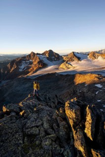 Mountaineers in front of a picturesque high mountain landscape at sunrise with alpenglow, glacier