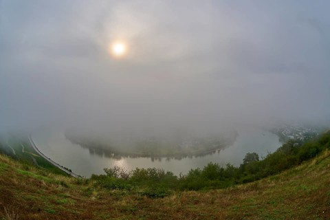 A river is covered by fog while the sun shines through the clouds, summer, Rhine bend Boppard,
