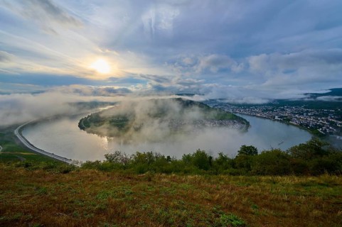 Misty river landscape in the morning light, surrounded by hills and clouds, summer, Rhine bend
