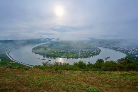 River with bend and cargo ship in the morning fog with light cloudy sky, summer, Rhine bend