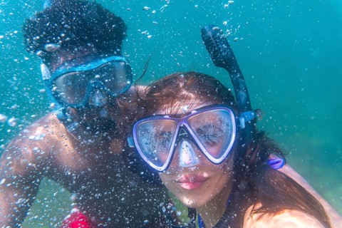 Young couple exploring the underwater world, enjoying their snorkeling adventure in crystal clear