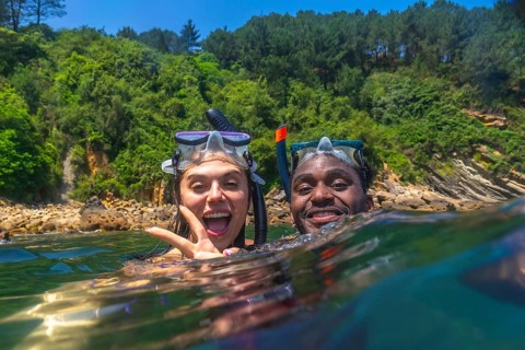 Interracial couple snorkeling together in the vibrant ocean, enjoying a fun filled summer vacation