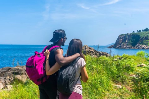 Couple savoring a stunning ocean view during a summer hike, celebrating the beauty of nature and