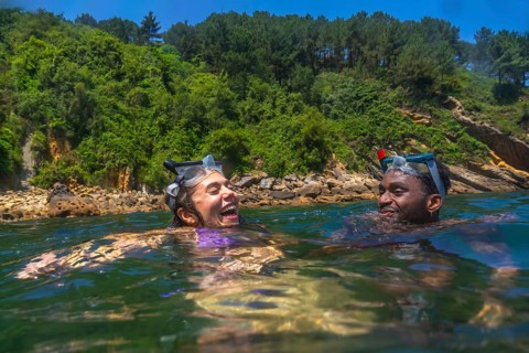 Tourists wearing snorkeling masks, laughing joyfully while enjoying a sunny summer vacation in the