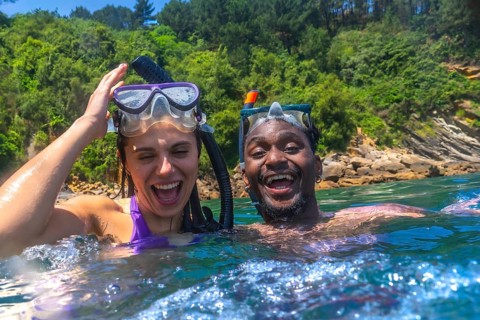 Interracial couple enjoying a fun snorkeling adventure in the vibrant ocean, laughing and sharing