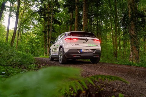 Car with glowing tail lights drives through green forest path, surrounded by nature, Deer E-