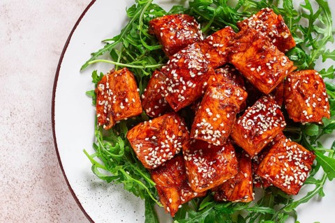 Fried salmon slices, teriyaki with sesame seeds, with arugula salad, top view