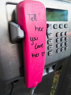 Telephone receiver of a Telekom payphone with the inscription Tell her you love her in Wuppertal,