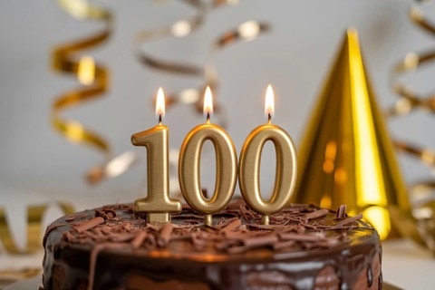 Chocolate cake with golden candles spelling 100. Celebration of longevity and reaching 100 years