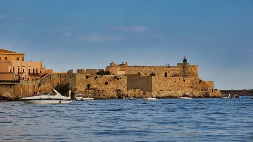 Castello Maniace, Maniace sea fortress, old defence defence tower by the sea with passing boats