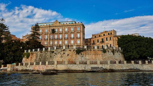 Elevated wall with historic buildings and lush vegetation in the coastal area, boat trip around the