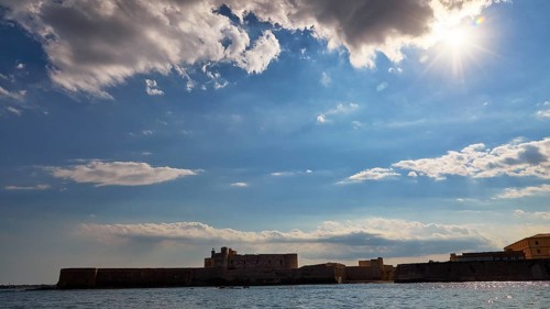 Castello Maniace, sea fortress Maniace, coastal fortress in sunlight under a cloudy sky, boat trip