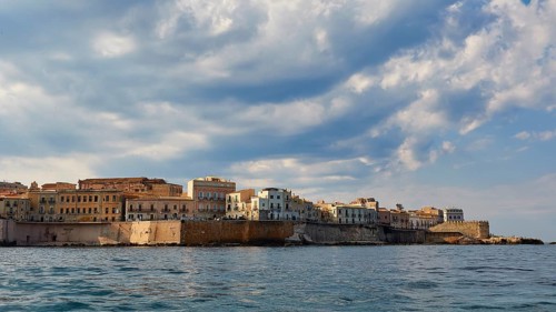 City along the coast with high clouds on the horizon, boat trip around the island of Ortigia, Isola