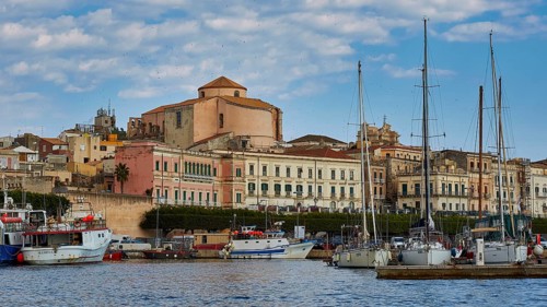 Harbour view with yachts and old buildings under a slightly cloudy sky, boat trip around the island
