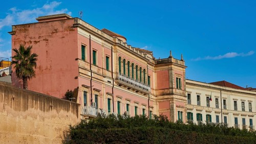 Pink historic building with many windows under a blue sky, Ortigia Island, Isola di Ortigia,
