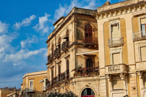 Close-up view of historic buildings with balconies and windows under blue sky, Ortigia Island,