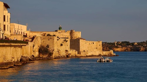 Castello Maniace, Maniace sea fortress, Mediterranean landscape with historic buildings and boat in