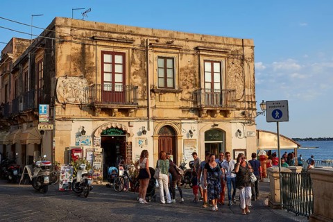 Lively streets with shops and views of the sea, surrounded by old town architecture, Ortigia