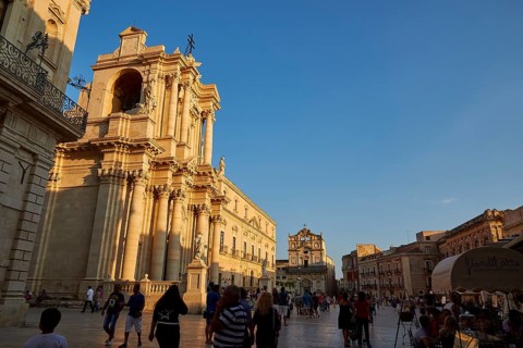 Cathedral of Syracuse, people strolling by an impressive cathedral on a square at sunset, Ortigia