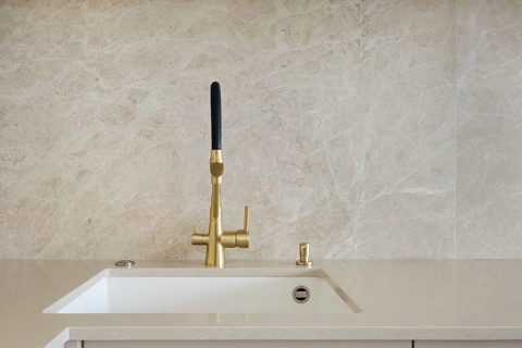 Modern kitchen faucet design with gold finish and minimalist aesthetic in bright interior space