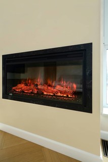 An electric fireplace is set into a wall in a bright living room. Flickering flames illuminate the