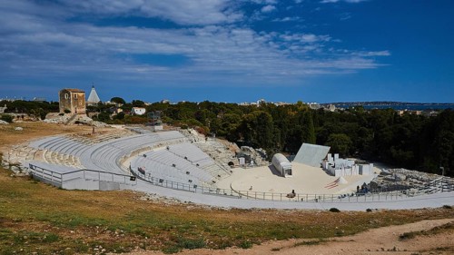 Greek amphitheatre, view of a large ancient amphitheatre with surrounding nature and blue sky with